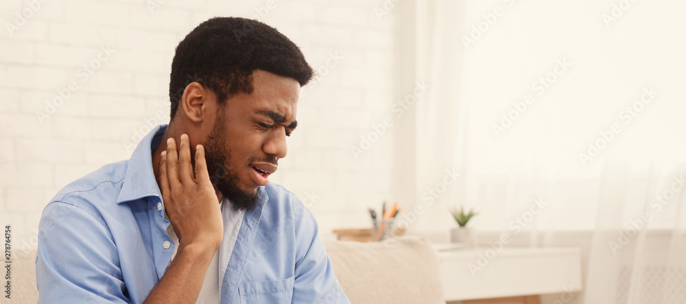 African-american man suffering from neck pain at home African-american man suffering from neck pain at home