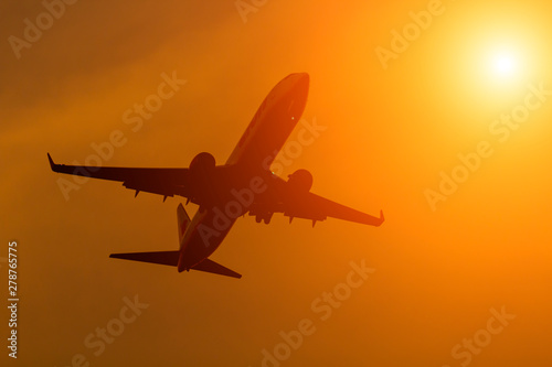 Silhouette comercial airplane flying on sunset.