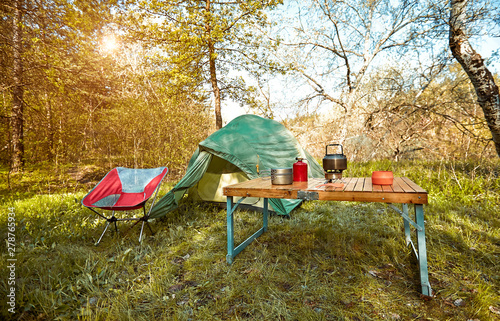 Camping in the woods with a backpack and a tent on the banks of the river .