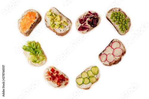 sandwiches or tapas prepared with bread and tasty ingredients. Could be nice food for healthy breakfast ot lunch. Copy space for your text centered in the shape of a heart