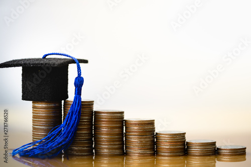 Graduation hat on coins money on white background. Saving money for education or scholarship concepts. Conception of education fee, education expenses, school tuition cost, graduation cap with coin. photo