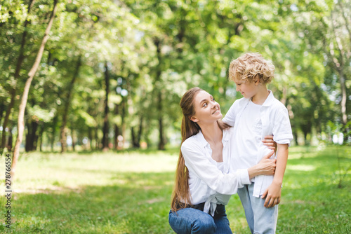 beautiful smiling mom hugging son in park during daytime