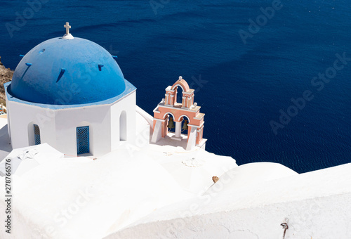 Whitewashed church and blue dome in the village of Fira on the idyllic island of Santorini