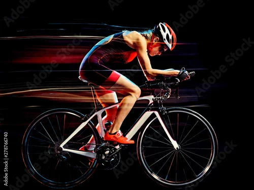 Fototapeta samoprzylepna jeden kaukaski kobieta triathlon triathlete rowerzysta studio rowerowe strzał na białym tle na czarnym tle z efektem malowania światłem