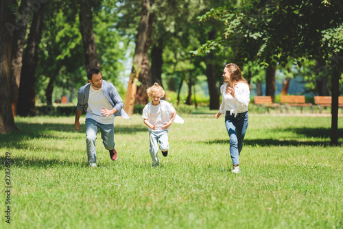 happy family in casual clothes running in park during daytime