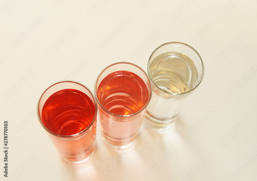 Three glasses of red and transparent liquid on white background, São Paulo, Brazil Three glasses of red and transparent liquid on white background, São Paulo, Brazil