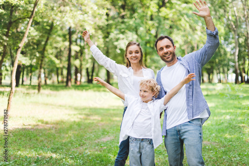 excited family with outstretched hands looking at camera in park