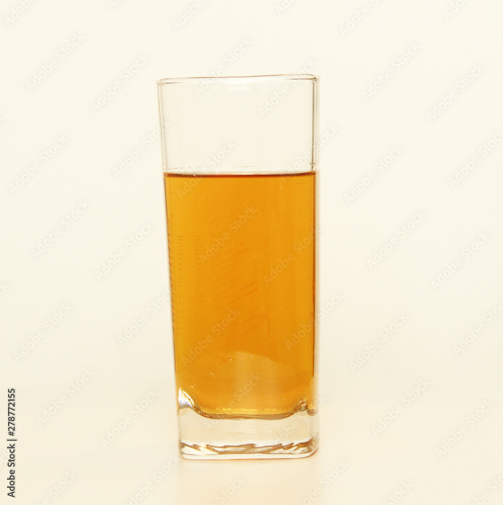One glass of yellow and transparent liquid on white background, São Paulo, Brazil One glass of yellow and transparent liquid on white background, São Paulo, Brazil