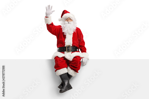 Santa claus sitting on a panel and waving photo