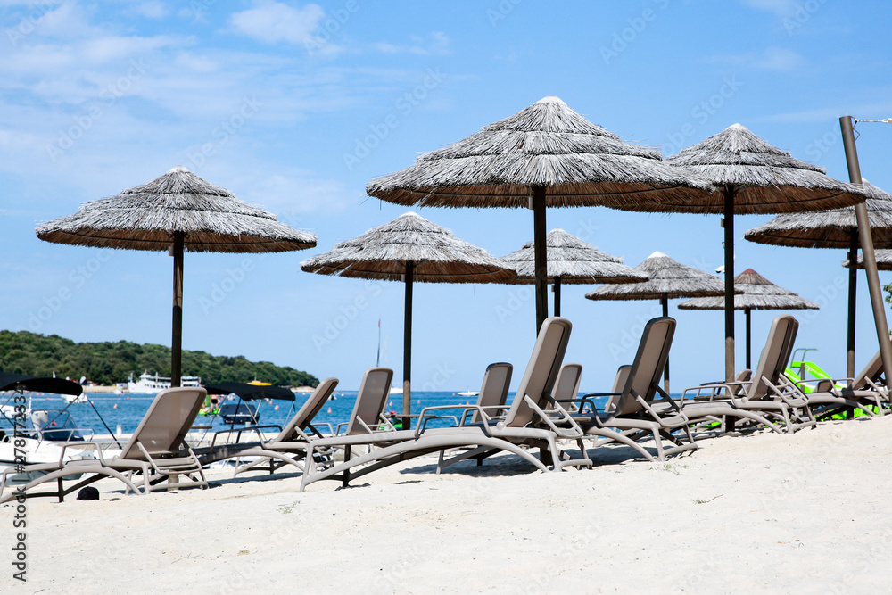 Armchairs with bamboo umbrellas and hammocks on sandy beach
