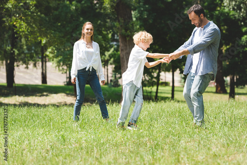 family spending time together, father holding hands with son in park