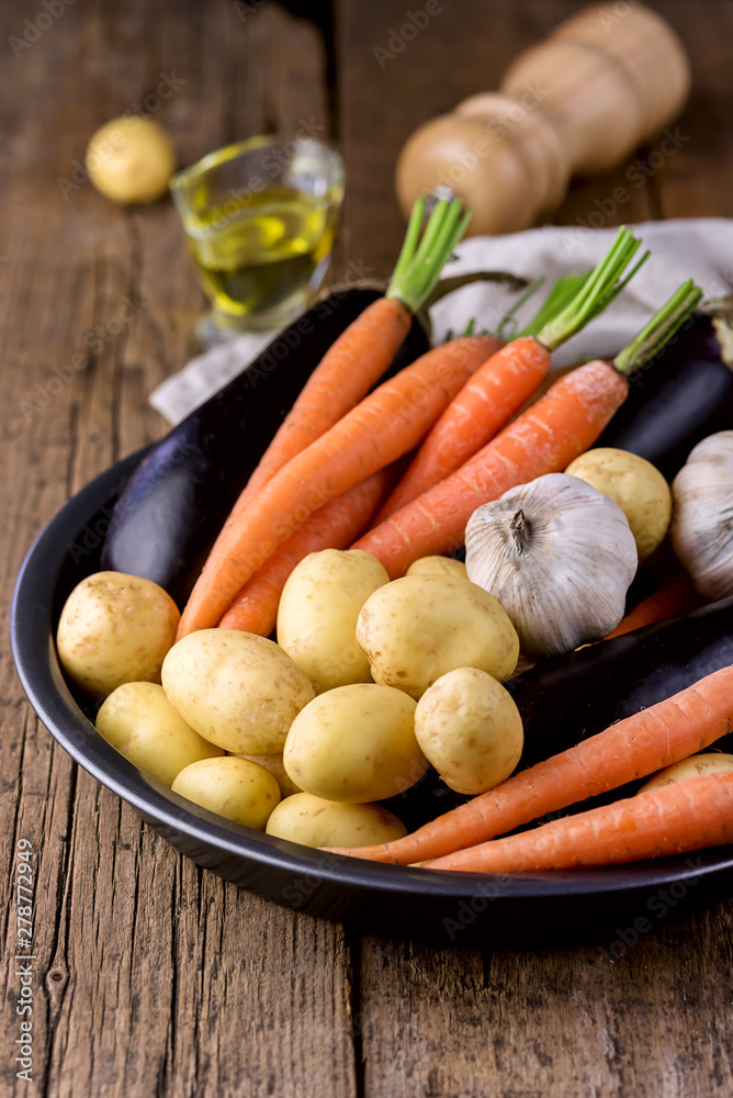 Raw Potatoes Carrot Garlic and Eggplant on Black Plate Variety of Raw Vegetables ready to Cook Fresh Natural Vegetables Organic Healthy Food Olive Oil Pepper Pot Wooden Background Vertical Raw Potatoes Carrot Garlic and Eggplant on Black Plate Variety of Raw Vegetables ready to Cook Fresh Natural Vegetables Organic Healthy Food Olive Oil Pepper Pot Wooden Background Vertical