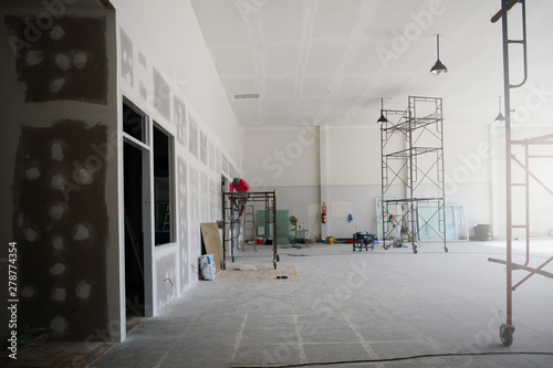 the iron scaffoldings on tile ground and the black lamp on  the ceiling with the labor while  renovation  the old office photo