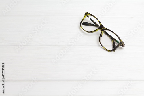 Modern black-green glasses on white wooden background. Minimalism. Front view