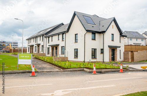 Newly buil houses on sale in a housing development in Scotland on a cloudy summer day. The houses have solar panels on the roof. photo