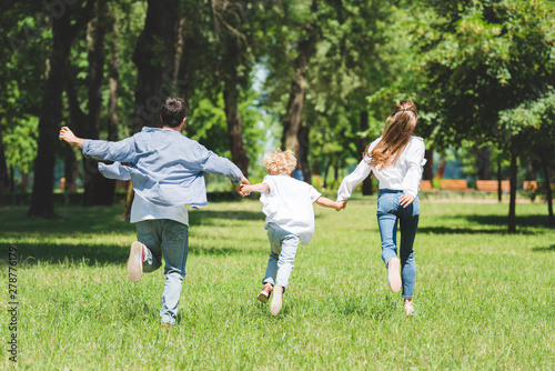 happy family holding hands and running in park during daytime
