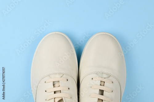 White leather casual shoes on a blue background. Copy space.