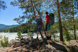 Young boys hiking in Altai mountains, standing on a rock near the river and admire amazing view.
