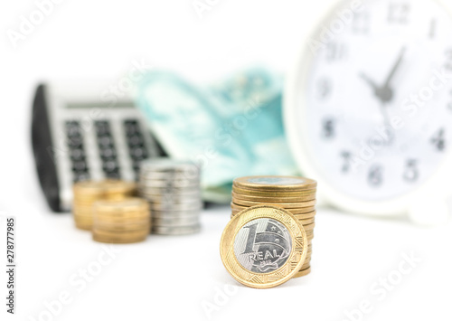 Close-up Brazilian currency money, calculator and alarm clock. White background. Coins of savings. Brazil. Growing business and future concept, coins stack.