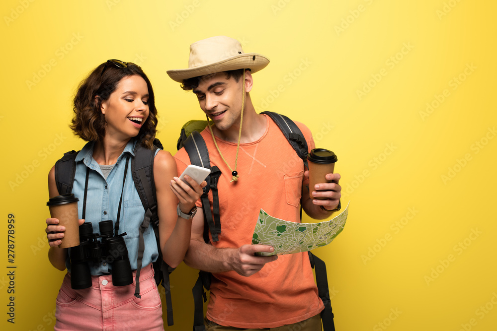 cheerful woman showing smartphone to man with geographic map on yellow background cheerful woman showing smartphone to man with geographic map on yellow background