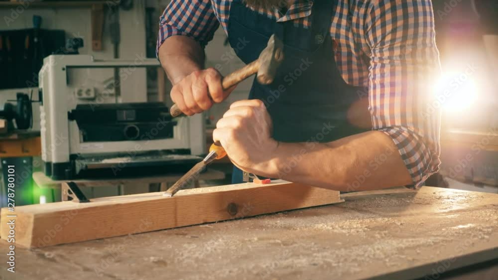 Male carpenter uses tools while working with wood.