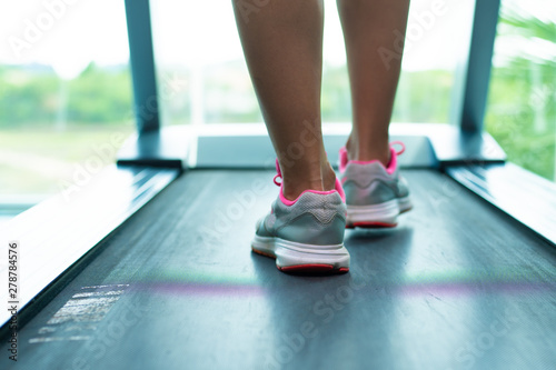 Close up womans legs in pink sneakers on a. Treadmill in the gym