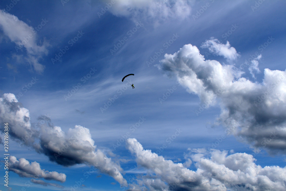 A parachute is in the amazing sky near white clouds.