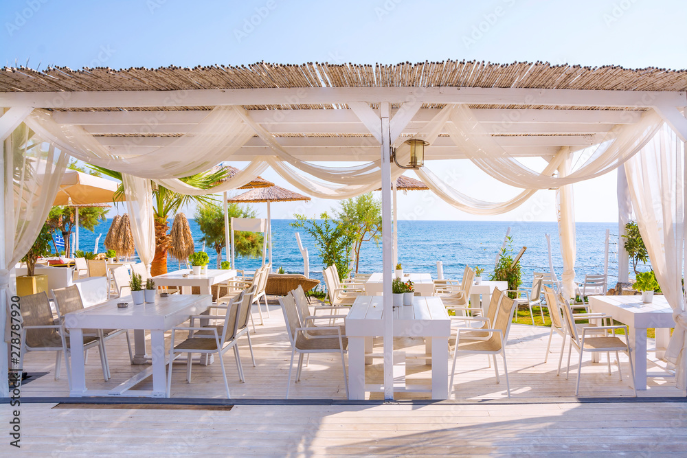 Outdoor restaurant with a beautiful view of the Mediterranean Sea on a sunny summer morning, Greece, Europe.