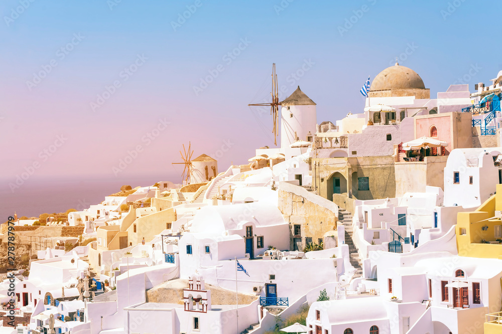 Beautiful view of fabulous picturesque village of Oia with traditional white houses and windmill in Santorini island at sunset, Greece