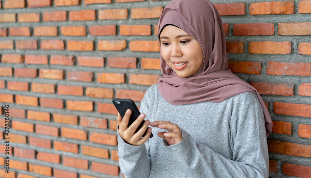 Naklejka premium close up young asian muslim woman holding smartphone for surf the net and watching media or shopping online , woman lifestyle concept
