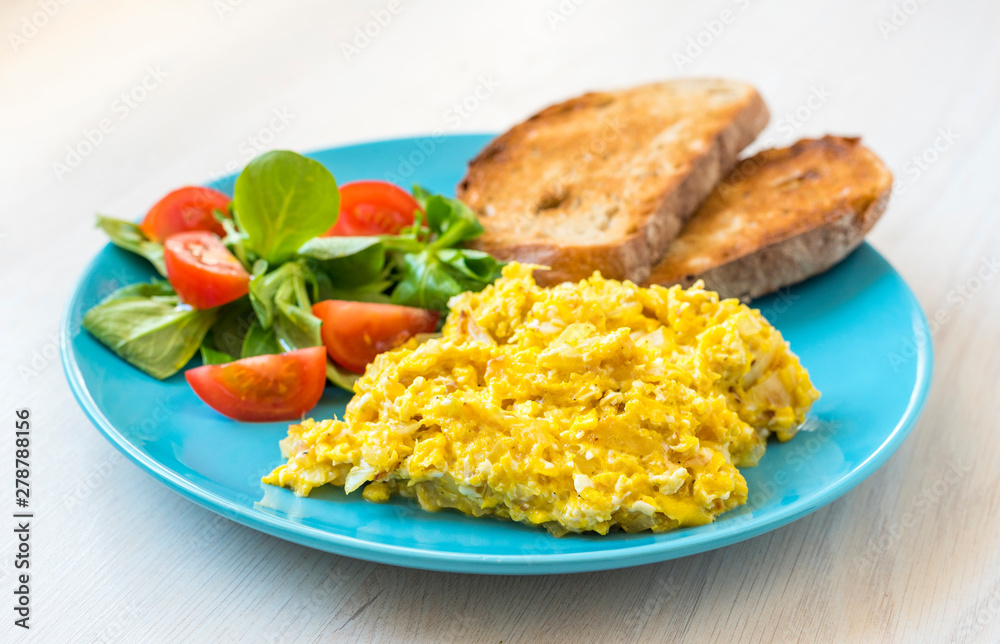 Scrambled eggs with toasted bread and tomato salad Scrambled eggs with toasted bread and tomato salad