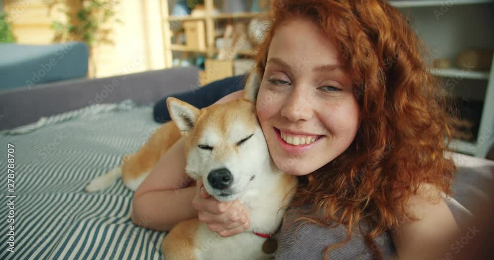 Close-up portrait of attractive young girl and pedigree dog lying on couch kissing looking at camera having fun expressing love. People and animals concept. Close-up portrait of attractive young girl and pedigree dog lying on couch kissing looking at camera having fun expressing love. People and animals concept.