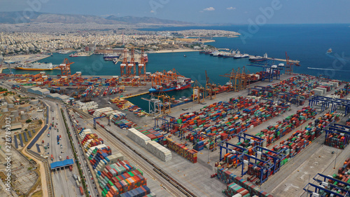 Aerial drone view of industrial cargo shipment and logistics port terminal with container trucks, ships and cranes