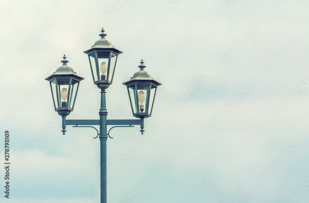 Old Street light. The sky with thunderclouds. Electric lighting of the modern city. Beautiful vintage lantern.