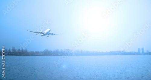 Plane over the river. Evening landscape and sun.