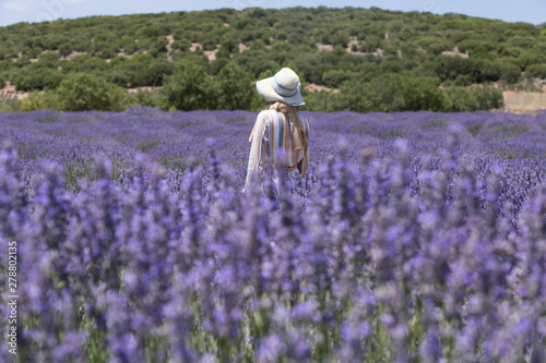 the woman wearing colorful dress and wicker hat in the lavender field take photo.