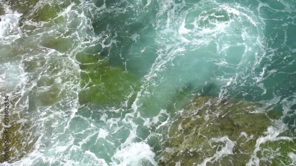 Foamy waves break on a rocky shore on a sunny, clear day Foamy waves break on a rocky shore on a sunny, clear day