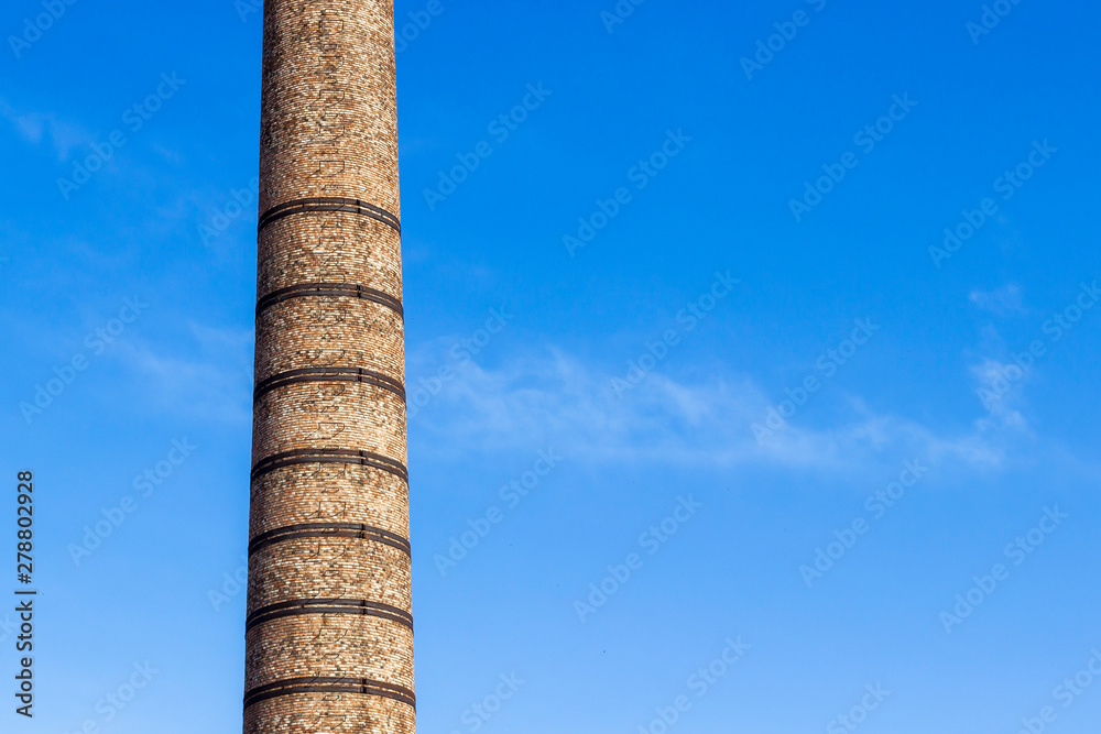 Horizontal cropped frame of contrasted colors masonry brick factory chimney at noontime