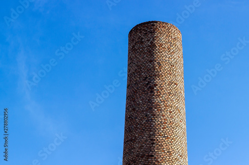 Horizontal frame of contrasted colors masonry brick factory chimney at noontime photo