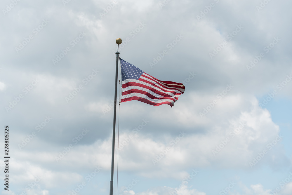 Lone stars and stripes on the flag of America waving in against a cloudy sky in summer.