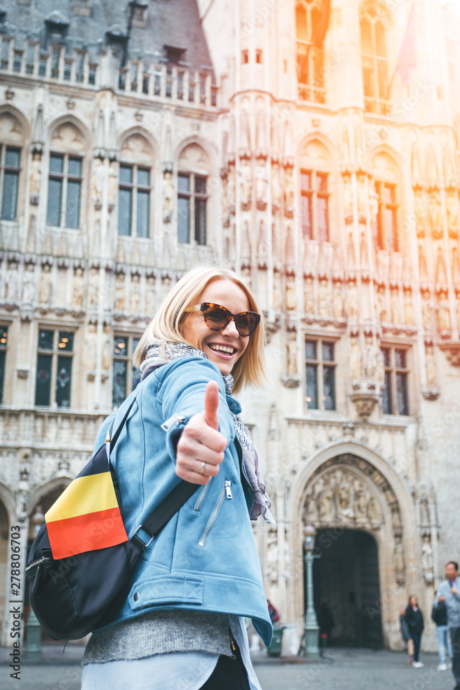 A female traveler stands on Grand Place Square in Brussels and shows her thumbs up, Belgium.