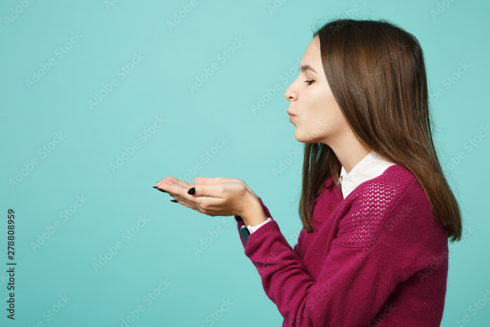 Side view of young brunette woman girl in casual clothes posing isolated on blue turquoise background studio portrait. People sincere emotions lifestyle concept. Mock up hold on hand palm copy space. Side view of young brunette woman girl in casual clothes posing isolated on blue turquoise background studio portrait. People sincere emotions lifestyle concept. Mock up hold on hand palm copy space.