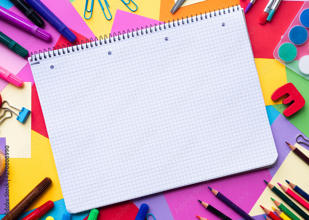 Notebook with school supplies on color background with copy space Notebook with school supplies on color background with copy space