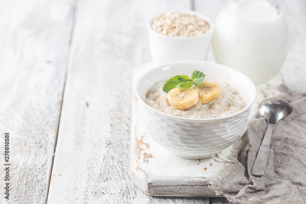 Bowl of oatmeal porridge with banana on white wooden rustic table, healthy breakfast, diet food. Bowl of oatmeal porridge with banana on white wooden rustic table, healthy breakfast, diet food.