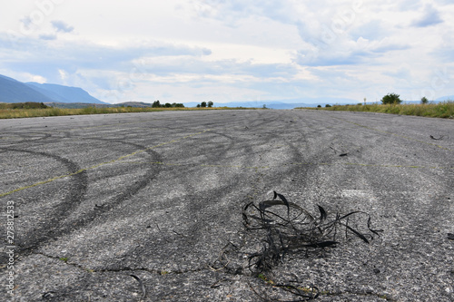 Pieces of car tires on asphalt surface with skid tracks. Marks of drifting cars on racetrack surface. Former runway near Sapareva Banya, Bulgaria, now used for car races