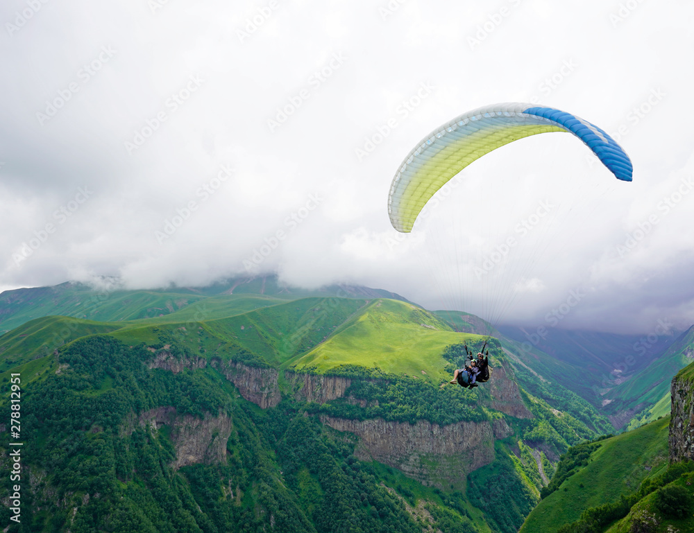 Tandem paragliding, green mountain valley on a cloudy day. Caucasus, Georgia Tandem paragliding, green mountain valley on a cloudy day. Caucasus, Georgia