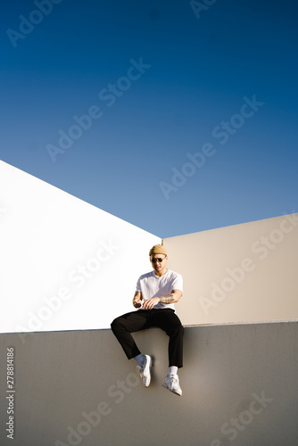 Young man wearing knit hat sitting on wall