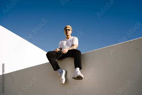 Young man wearing knit hat sitting on wall photo