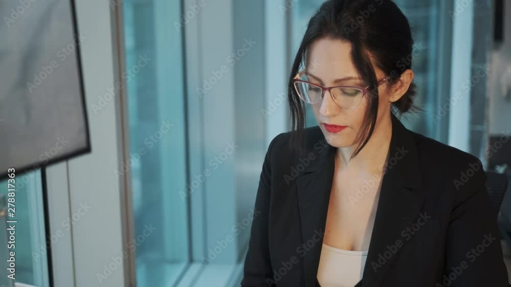 Closeup portrait of a young woman in a business suit at workplace. business woman working on computer sitting by the window in the office Closeup portrait of a young woman in a business suit at workplace. business woman working on computer sitting by the window in the office