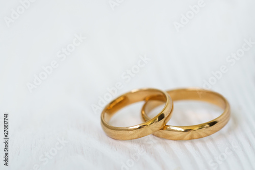 Wedding background with two rings on white wood.